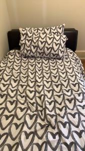 a bed with a black and white comforter and two pillows at Small Cozy Room in Calgary