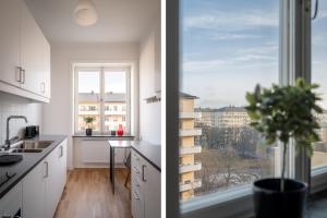 eine Küche mit weißen Schränken, einem Fenster und einer Pflanze in der Unterkunft Libevi 1 in Stockholm