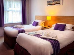 a hotel room with two beds with purple pillows at The Tor Park Hotel in Torquay