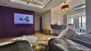 a living room with a couch and a tv on a wall at 2 BR Condo Free Wifi & Netflix - Circulo Verde, Eastwood Libis, Quezon City in Manila