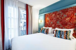 a bedroom with a large white bed and a red wall at Hotel de Fleurie - Saint-Germain-des-Pres in Paris