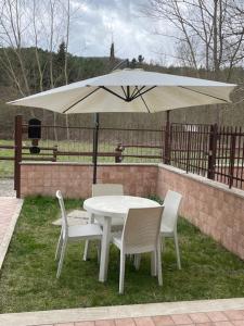 einen weißen Tisch und Stühle mit Sonnenschirm in der Unterkunft le piccole sorgenti in Bagni San Filippo