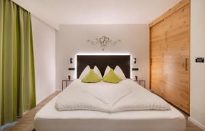 ein Schlafzimmer mit einem weißen Bett und gelben Kissen in der Unterkunft Pension Florian in Burgeis