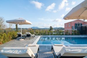 a swimming pool with chairs and an umbrella at Castelia Luxury Villas in Agios Ioannis