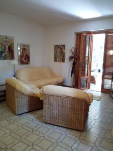 sala de estar con 2 reposapiés de mimbre y 2 sillas en Villetta Pescespada, en Grosseto