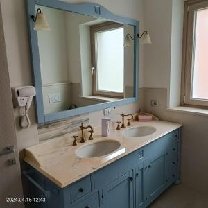 La salle de bains est pourvue de 2 lavabos et d'un grand miroir. dans l'établissement Villa Mariana Bed and Breakfast, à Saluces