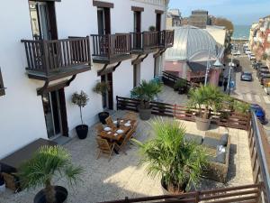 Un balcón con mesa, sillas y plantas en macetas. en L ecrin Villersois terrasse vue mer, en Villers-sur-Mer