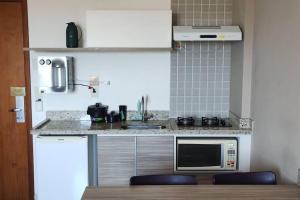 cocina con fregadero y microondas en Apartamento Privê Riviera 10, en Caldas Novas