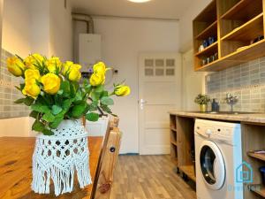 a vase of yellow flowers sitting on a table in a kitchen at Swan Room in Gdańsk