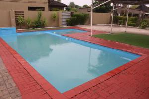una piscina con agua azul y ladrillos rojos en Makgovango Hotel, en Gumare
