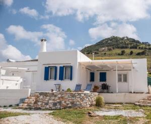 a white house with blue windows and a hill at Olympio Luxury Studio Paros in Kampos Paros