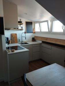 a kitchen with white cabinets and a sink and windows at Fargeot in Saint-Jean-de-Luz