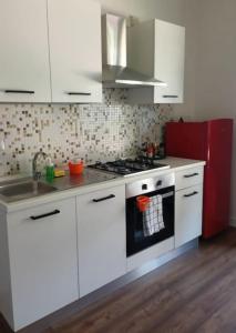 een keuken met witte kasten en een fornuis met oven bij Jitaku MERAKI in Cagliari