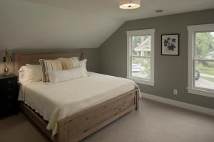 a bedroom with a bed with white sheets and two windows at Chaska Charmer in Chaska