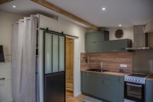 a kitchen with gray cabinets and a sink and a shower at Charmant studio in Saint-Aubin-de-Médoc