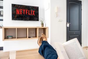 a person reading a book in front of a tv at CALMA Apartments in Benidorm