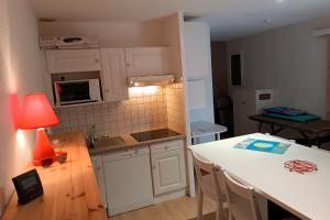 a kitchen with white cabinets and a table with a lamp at Pretty house with double terrace near the ocean in Moliets-et-Maa