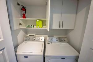 Il comprend une petite cuisine avec des placards blancs et une cuisinière. dans l'établissement Modern Condo 2BR 4 beds AC Wi-Fi Free Parking, à Laval