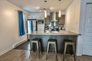 a kitchen with a counter and stools in a kitchen at Modern Condo 2BR 4 beds AC Wi-Fi Free Parking in Laval