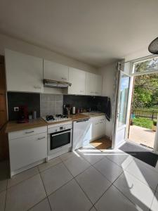 a kitchen with white appliances and a large window at Gîte Les Longères in Montazeau