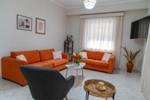 una sala de estar con 2 sofás naranjas y una mesa. en 50 DANAIDES, en Argos