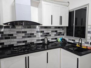 una cucina con armadietti bianchi e ripiani neri di E! Best Apartment a Padang Serai