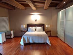 Cette chambre comprend un lit avec des draps blancs et du parquet. dans l'établissement Crivelli-Penthouse, à San Severino Marche