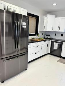 a kitchen with a stainless steel refrigerator and white cabinets at Saugerties Modern Charm with Creekside access and views in Saugerties