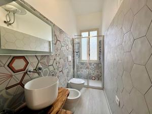 een badkamer met een wastafel, een toilet en een spiegel bij Nuovissimo appartamento a Marina di Grosseto in Marina di Grosseto