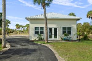 a white house with palm trees in front of it at 2/1 Riverside Retreat with Loft in Fort Pierce