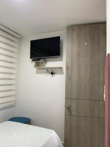 a bedroom with a bed and a flat screen tv on the wall at Ricaurte Cundinamarca La Aldea - hermosa vista a las piscinas in Ricaurte