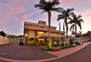 a building with palm trees in front of it at Garden Hotel in Ribeirão Preto