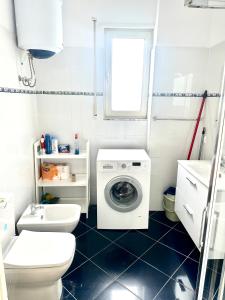 een witte badkamer met een wasmachine bij Family Seaview Ap. Korabi 304 in Durrës