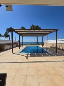 uma piscina sob um pavilhão junto à praia em Fabulous beach front house with pool em Lárnaca