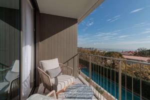 een balkon met 2 stoelen en een zwembad bij Legacy Hotel Cascais, Curio Collection By Hilton in Cascais