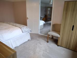 a bedroom with a bed and a chair and a mirror at Robin Hill Cottage in Amesbury