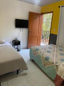 1 dormitorio con 1 cama, TV y ventana en Mirador Hotel Aoki, en Valle de Ángeles