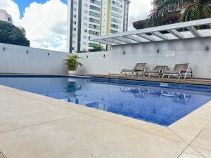 a swimming pool with chairs next to a building at Flat 2313 - Crystal Place in Goiânia