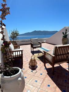 eine Terrasse mit Stühlen und einem Tisch mit Blick auf das Wasser in der Unterkunft ANTICA DIMORA Santa Marina Salina in Santa Marina Salina