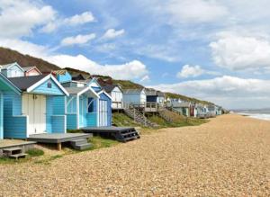 a row of colorful houses on a beach at The perfect New Forest / coastal base. Sleeps 9. in Lymington