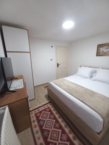a bedroom with a bed and a desk with a television at VodaHouse in Gjirokastër