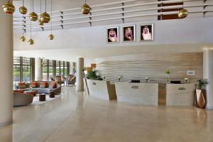 a lobby with a waiting area with couches and portraits at Marriott Riyadh Diplomatic Quarter in Riyadh