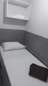 una cama blanca con una bolsa negra sentada en ella en Phos Hostel, en Araxá