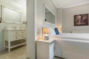 a white bedroom with a bed and a sink at Provence in Arad