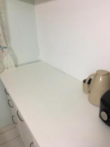 eine Ecke eines weißen Zimmers mit einer Teekanne in der Unterkunft Quarto no Jd. Satélite - Excelente localização na Zona Sul in São José dos Campos