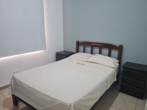 1 dormitorio con 1 cama blanca y 2 mesitas de noche en Habitaciones Matrimoniales en Playa Pulpos HOSPEDAJE DELFINES HOUSE, en Lurín