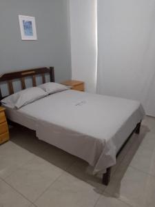 a bed sitting in a room with a white wall at Habitaciones Matrimoniales en Playa Pulpos HOSPEDAJE DELFINES HOUSE in Lurín