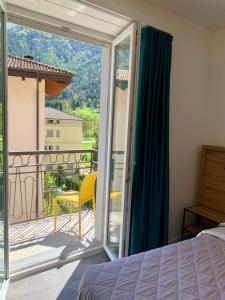 a bedroom with a bed and a balcony with a view at Hotel Locanda Alla Perla in Ledro