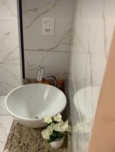 baño con lavabo blanco y flores en una encimera en Phos Hostel, en Araxá