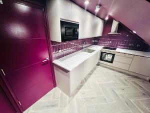 High Standard Room, Super Location في لندن: مطبخ بجدران أرجوانية ودواليب بيضاء